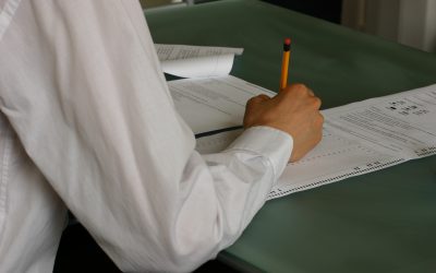 Student writing an examination paper at a desk